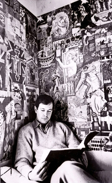 Joe against the collaged walls of his London flat.